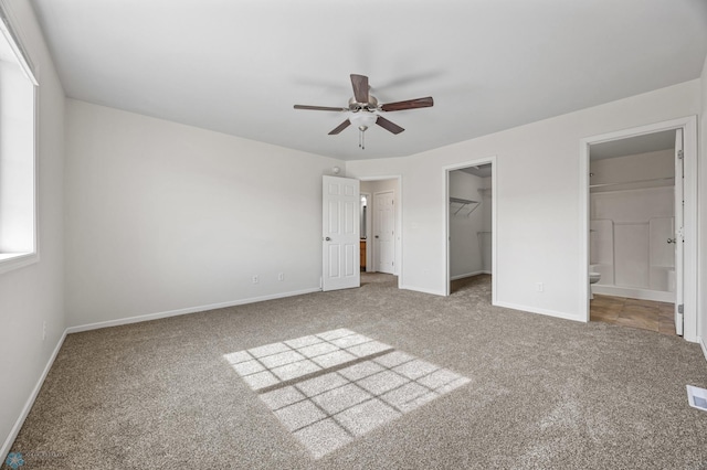 unfurnished bedroom featuring a spacious closet, a closet, baseboards, and carpet floors