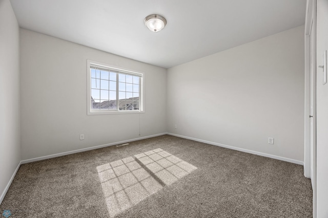 spare room with carpet flooring, visible vents, and baseboards