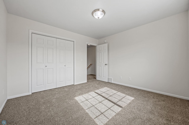 unfurnished bedroom with carpet, a closet, and baseboards