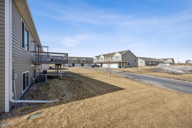 view of yard featuring a residential view, central AC unit, and a wooden deck