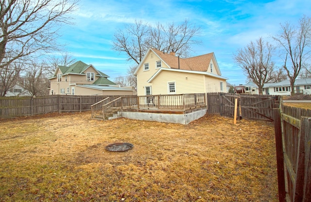 rear view of property featuring a fenced backyard, a lawn, and a wooden deck