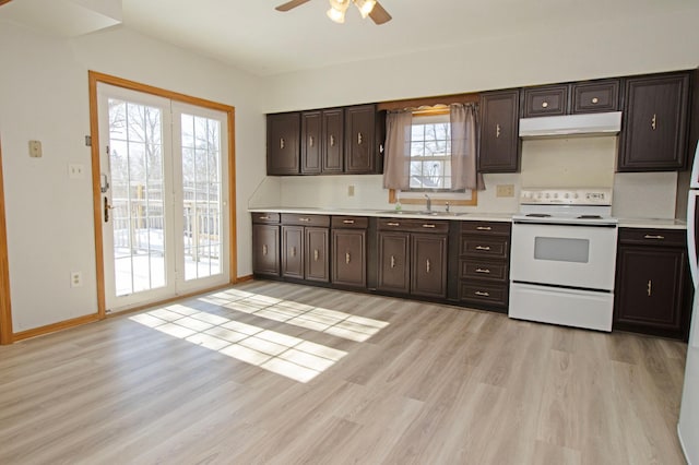 kitchen with under cabinet range hood, light countertops, light wood-style flooring, electric range, and a sink