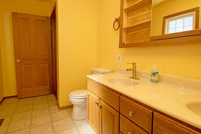 bathroom with a sink, baseboards, toilet, and double vanity