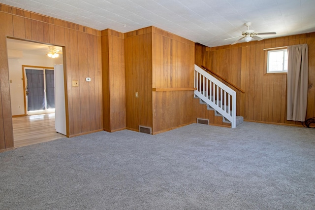 unfurnished living room featuring visible vents, ceiling fan, carpet flooring, and stairway