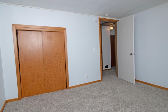 unfurnished bedroom with carpet, a closet, and baseboards