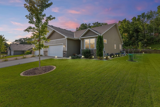 view of front of home featuring driveway, stone siding, a front yard, a shingled roof, and a garage