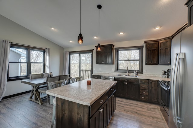 kitchen featuring wood finished floors, a sink, dark brown cabinetry, vaulted ceiling, and appliances with stainless steel finishes