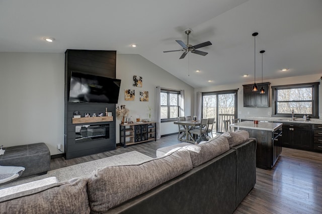 living area featuring a large fireplace, ceiling fan, lofted ceiling, recessed lighting, and dark wood-style flooring