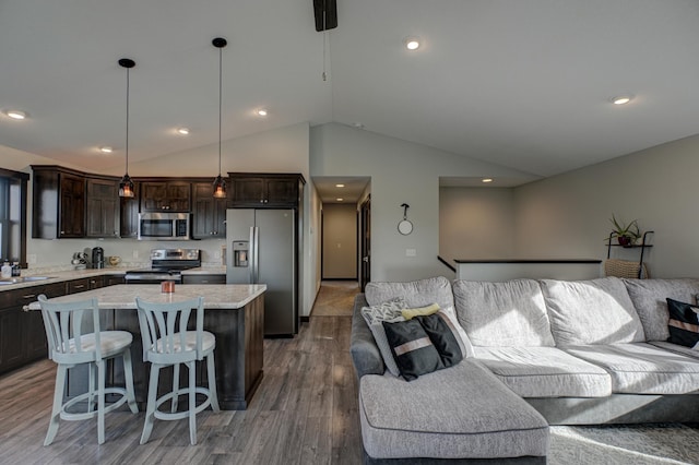 kitchen with open floor plan, a center island, dark brown cabinetry, appliances with stainless steel finishes, and light countertops