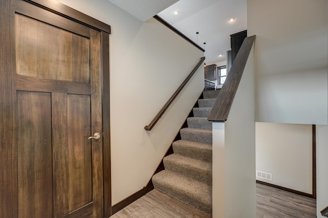 staircase with recessed lighting, wood finished floors, visible vents, and baseboards