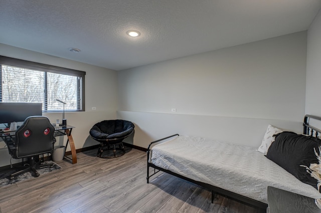 bedroom with wood finished floors, baseboards, and a textured ceiling