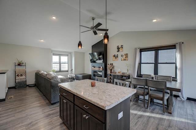 kitchen featuring light wood-type flooring, light countertops, ceiling fan, and vaulted ceiling