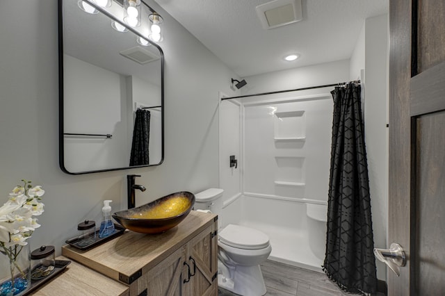 bathroom with a shower with curtain, vanity, toilet, visible vents, and wood finished floors