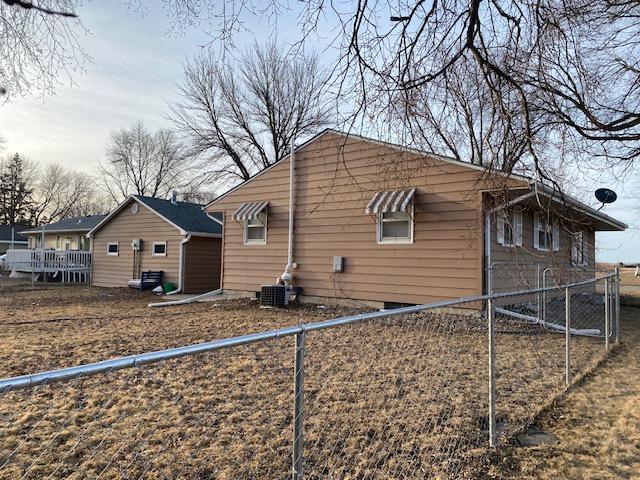 view of property exterior with central AC unit and fence private yard