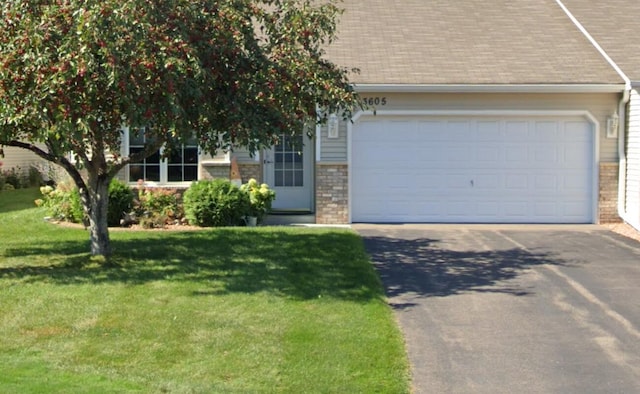 view of front facade featuring driveway, roof with shingles, a front yard, an attached garage, and brick siding