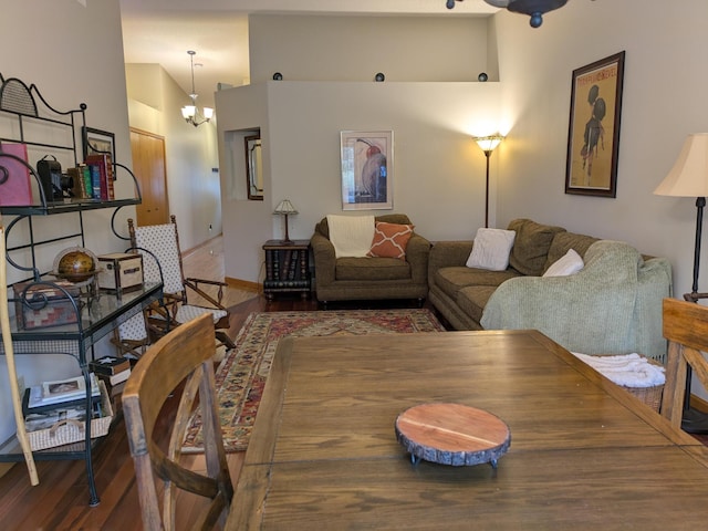 living room with a notable chandelier, wood finished floors, baseboards, and a towering ceiling