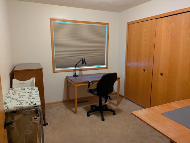 bedroom with a closet, light carpet, a textured ceiling, and baseboards