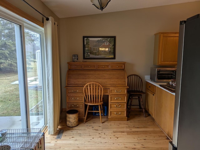 office area featuring light wood-type flooring and a toaster