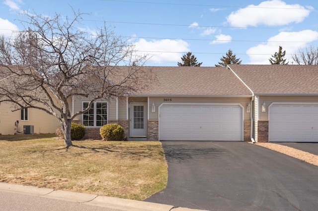 view of front of property featuring driveway, brick siding, a front yard, and central AC unit