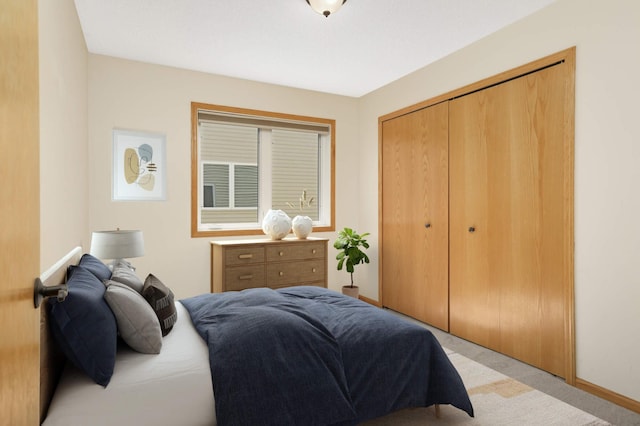 bedroom with a closet, light colored carpet, and baseboards