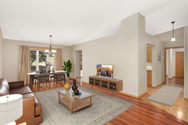 living area featuring a chandelier, wood finished floors, baseboards, and vaulted ceiling