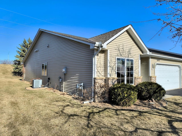 view of side of property with a garage, a yard, and central air condition unit