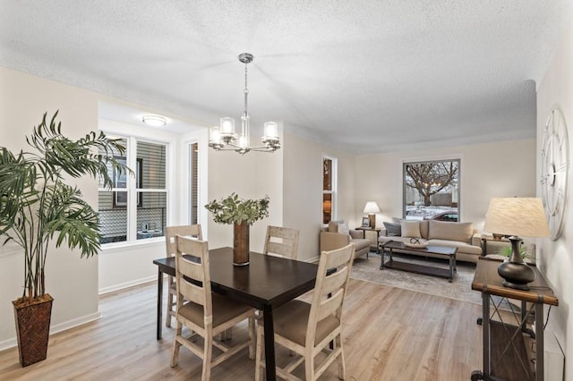 dining space with baseboards, a notable chandelier, a textured ceiling, and light wood-style floors