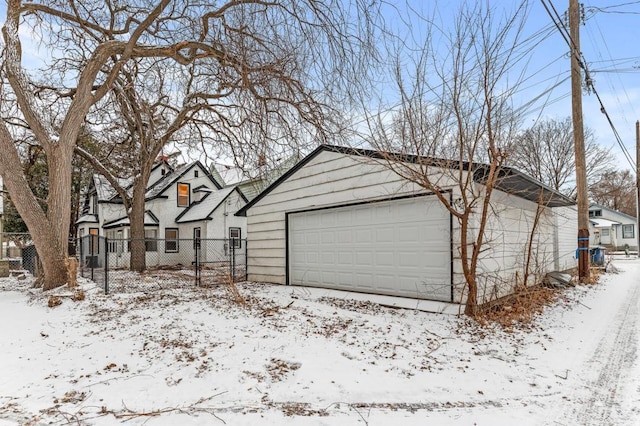 snow covered garage featuring a garage, a residential view, and fence