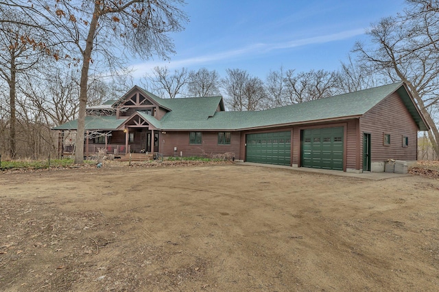 view of front facade featuring a porch, roof with shingles, and a garage