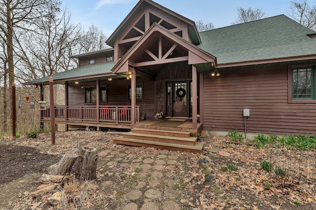chalet / cabin with a shingled roof and covered porch