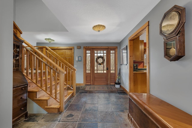 entrance foyer featuring baseboards, stairway, and stone tile flooring