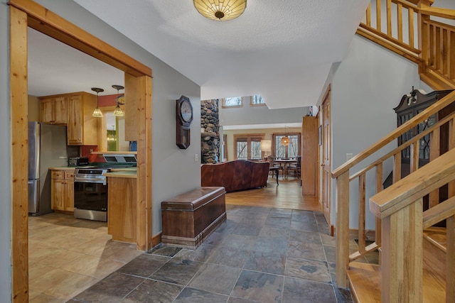 hallway featuring baseboards, stone finish floor, and stairway