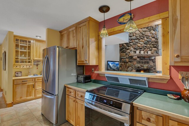 kitchen featuring light countertops, stainless steel appliances, hanging light fixtures, and glass insert cabinets