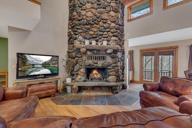 living room with baseboards, a towering ceiling, french doors, and a fireplace
