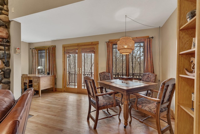 dining space with light wood-style floors, baseboards, a healthy amount of sunlight, and french doors