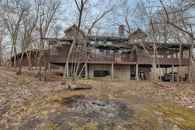 rear view of property featuring a wooden deck, a chimney, and a sunroom