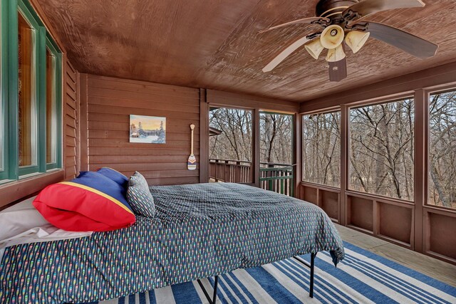 bedroom with wooden walls and a ceiling fan