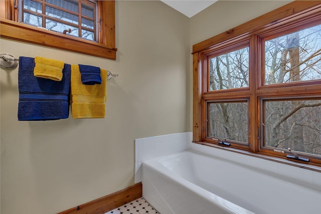 full bath with baseboards, a garden tub, and a healthy amount of sunlight