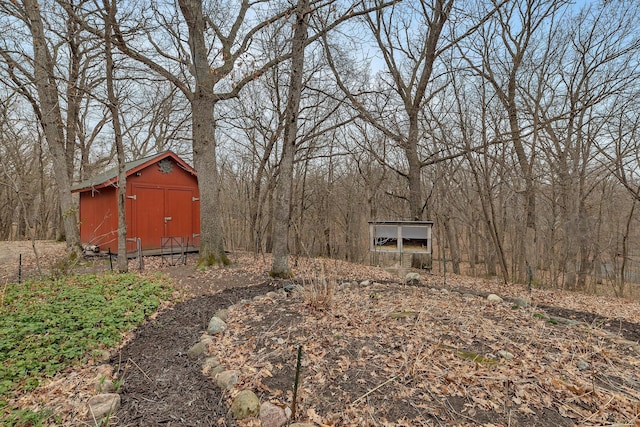 view of yard featuring a view of trees, an outbuilding, and a storage unit