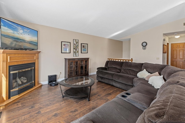 living area with baseboards, lofted ceiling, a fireplace with raised hearth, and wood finished floors