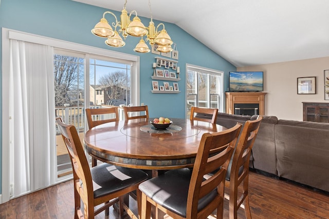 dining space with an inviting chandelier, a fireplace, lofted ceiling, and wood finished floors