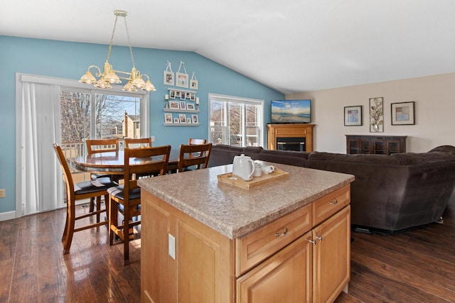 kitchen featuring a glass covered fireplace, a center island, dark wood-type flooring, and lofted ceiling