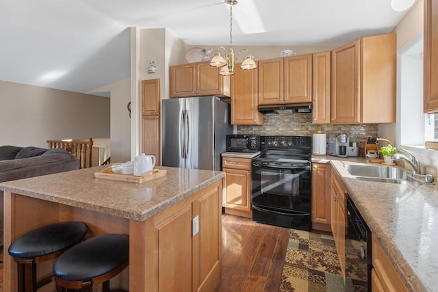 kitchen with a sink, black appliances, vaulted ceiling, under cabinet range hood, and backsplash