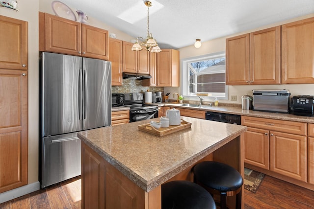 kitchen featuring under cabinet range hood, vaulted ceiling, dark wood-style floors, stainless steel appliances, and a sink