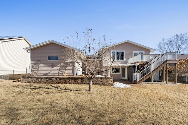 back of property with a wooden deck, a lawn, stairs, and fence