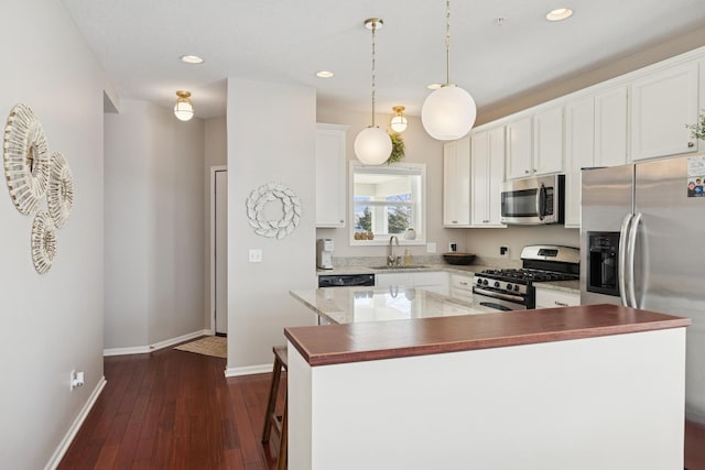 kitchen with dark wood-style flooring, appliances with stainless steel finishes, white cabinetry, and a sink