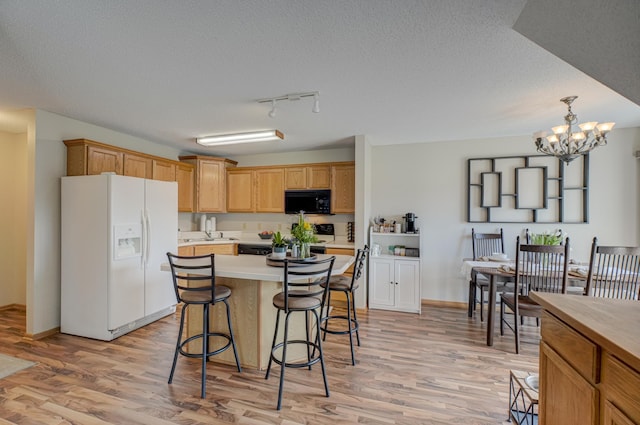 kitchen featuring white refrigerator with ice dispenser, a breakfast bar area, black microwave, and light countertops