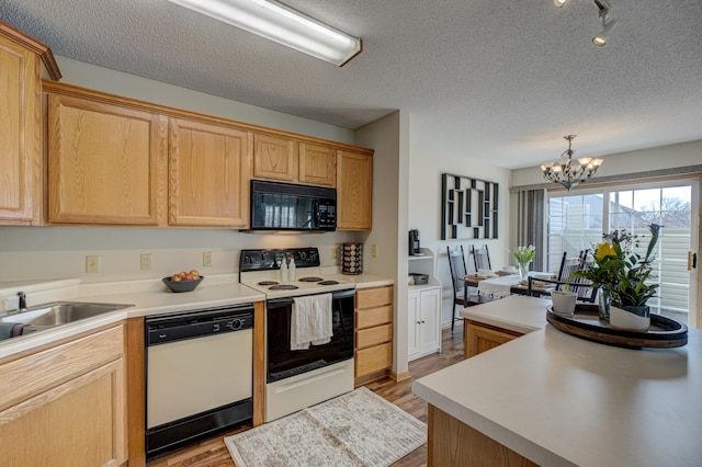 kitchen featuring black microwave, light countertops, electric range oven, white dishwasher, and a notable chandelier