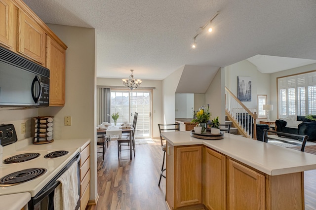 kitchen with electric range, light countertops, black microwave, a notable chandelier, and open floor plan