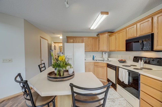 kitchen with light brown cabinets, white appliances, a textured ceiling, and light countertops